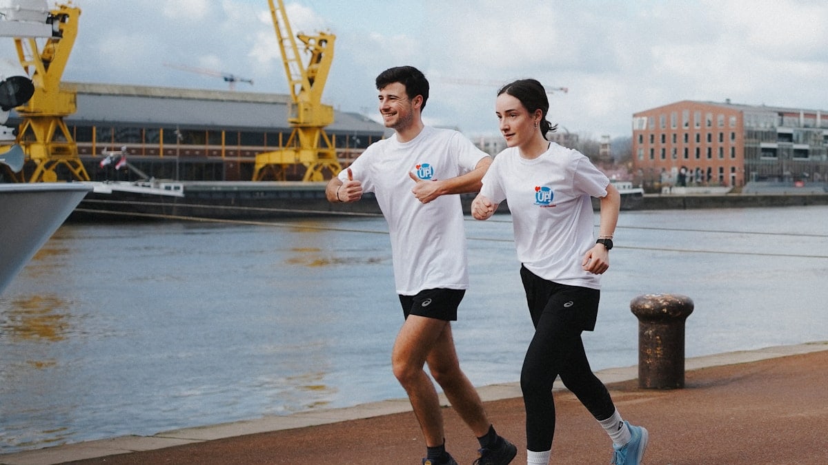 A couple is running near a waterfront.